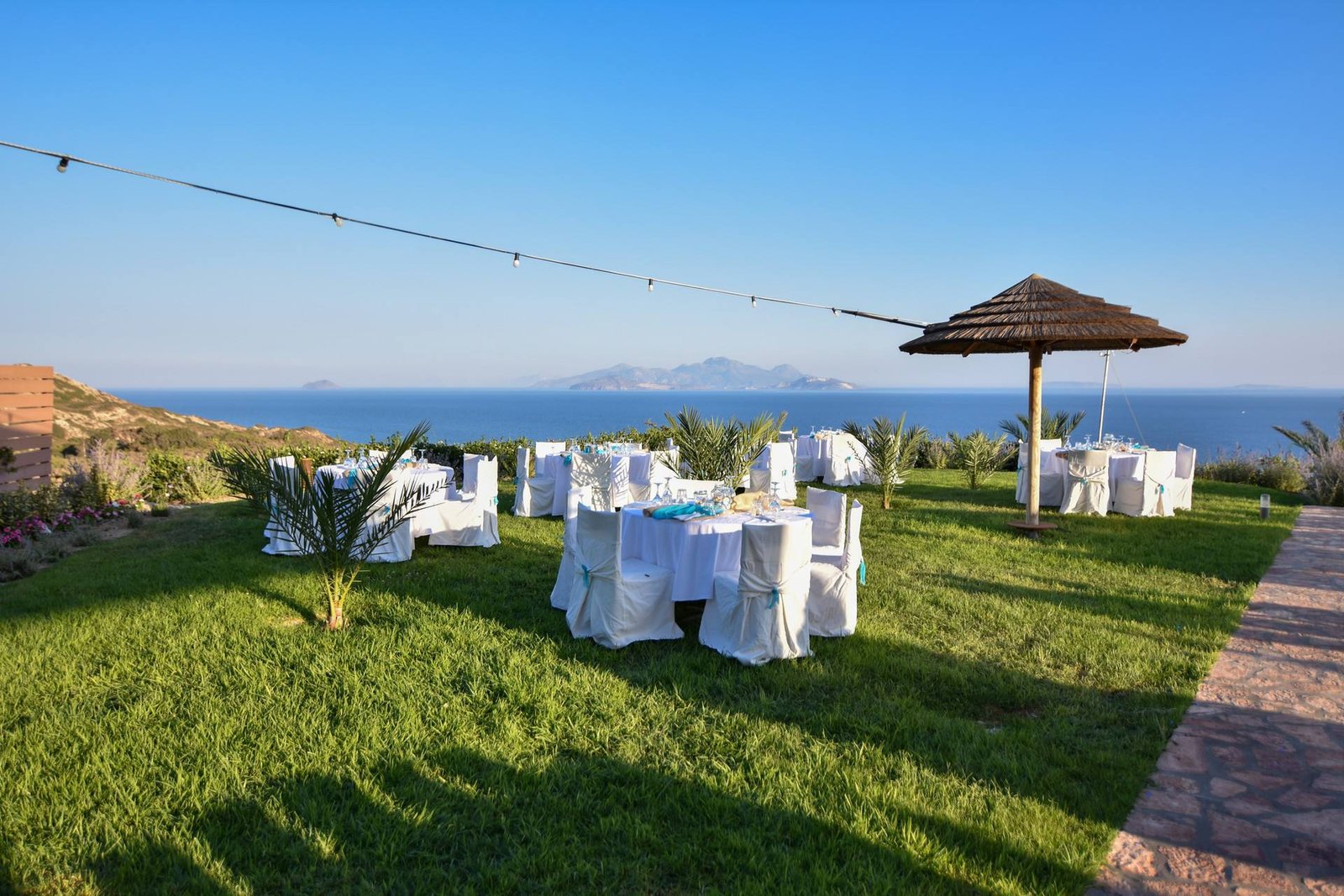 Dinner tables on the lawn with the Aegean behind