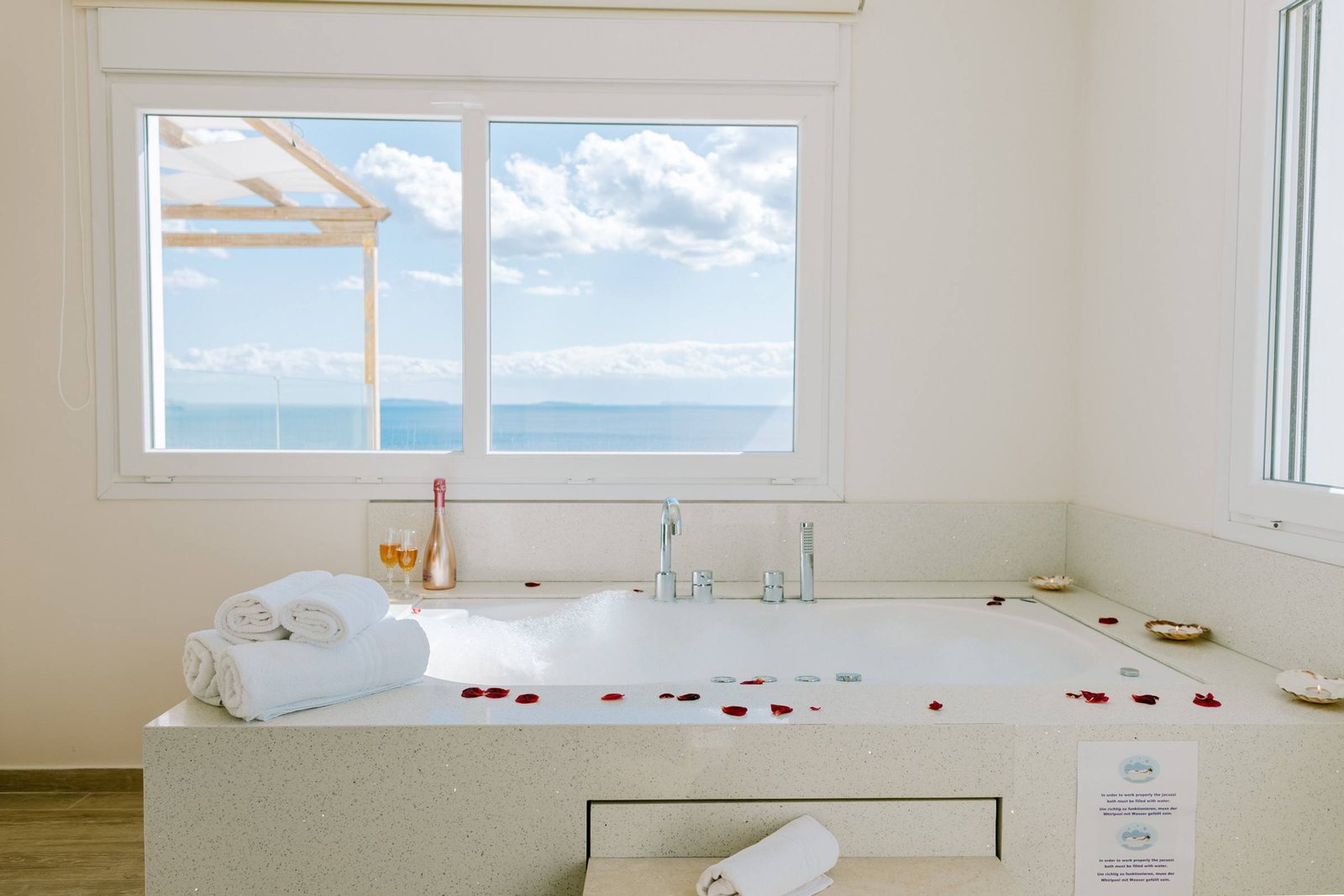 Jacuzzi with rose petals and prosecco, sea through the window